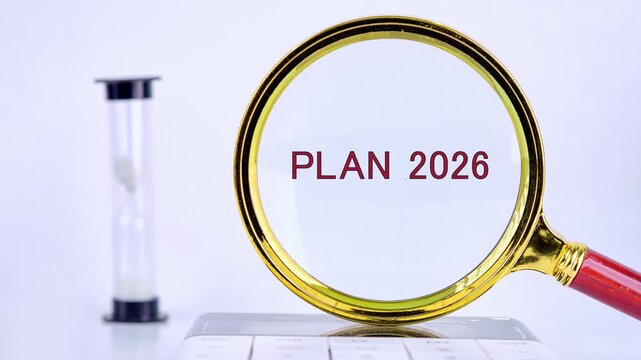 Scattered red letters become clear under a magnifying glass, resolving into PLAN 2026. An hourglass and keyboard are visible, suggesting a deadline