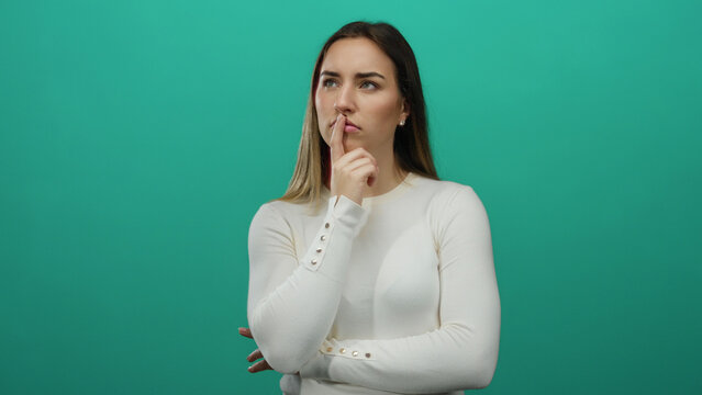 Woman thinking deeply, appears pensive and contemplative, wearing white shirt, isolated against solid green background, exhibiting thoughtful and reflective posture, blonde hair.