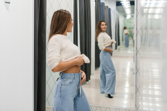 Woman Checking Fit Of Jeans In Dressing Room