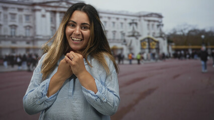 Fototapeta premium Woman with open mouth and hands gesturing in front of a grand building with tourists, nails and rings visible; surprise travel discovery.