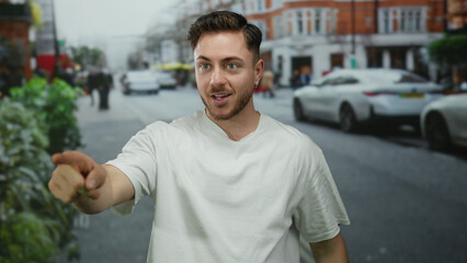 Young bearded man pointing excitedly in a lively urban street setting with cars and people passing by under a cloudy sky.