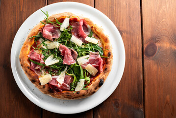 Pizza con rucola, scaglie di parmigiano e prosciutto crudo, cibo italiano 