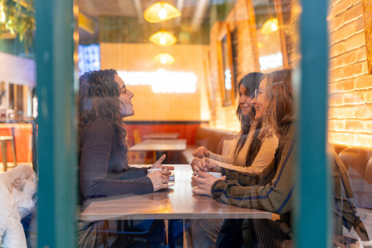 Women friends enjoying coffee and conversation in city cafe