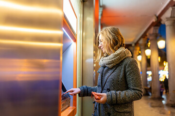 Woman withdrawing cash from bank machine at night