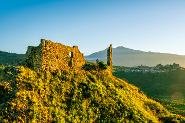 golden beautiful sunset landscape of mountain peak with ancient fortrees ruin on the top and...