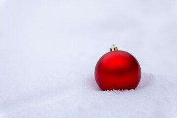 Red Christmas ball ornament on fresh snow with clean white background and copy space. Minimal winter holiday decoration ideal for Christmas design, seasonal advertising and festive branding.