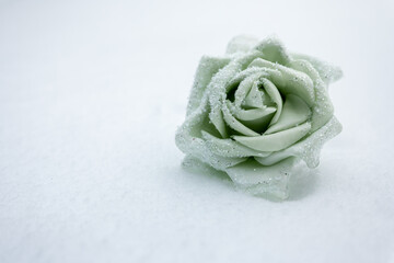 Mint green decorative rose with fine crystals on snow. Minimal winter still life with copy space, suitable for fairy tale themes, winter weddings, Christmas design and holiday backgrounds.