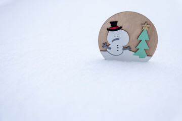 Wooden snowman decoration with Christmas tree standing in snow. Minimal winter scene with copy space, suitable for Christmas design, holiday cards, winter backgrounds and seasonal concepts.