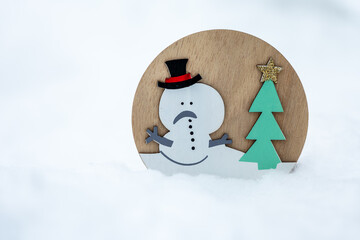 Wooden snowman decoration with Christmas tree standing in snow. Minimal winter scene with copy space, suitable for Christmas design, holiday cards, winter backgrounds and seasonal concepts.