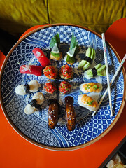 Sushi Platter on a large round plate with a blue pattern and bamboo chopsticks, top view