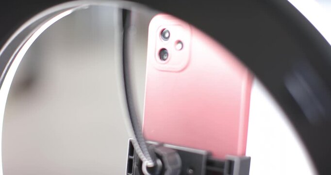 Autofocus engaging, sharpening focus on rose-gold smartphone inside LED ring, highlighting lenses