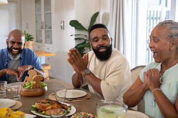 African American family sitting at kitchen table with lemonade pitcher roasted chicken, salad bowl © wavebreak3