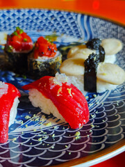 Sushi Platter, Japanese cuisine, sushi and rolls with tuna and caviar on a dark blue plate with a pattern