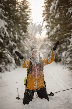 Woman playfully throws snow into the air while skiing in Maine