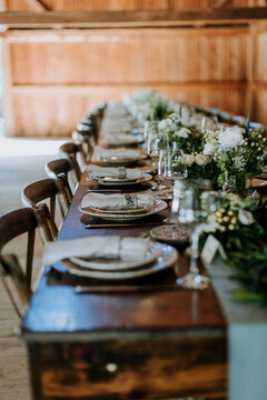 rustic table set for dinner with flower arrangements in a barn