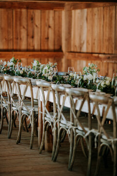long formal dinner table in a barn with flower arrangements