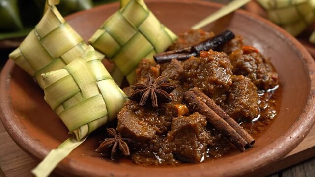 Traditional Indonesian dish with beef rendang and ketupat on a clay plate with star anise and cinnamon sticks