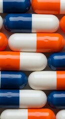 Assorted blue white and orange capsules arranged closely together in a pattern on a gray background
