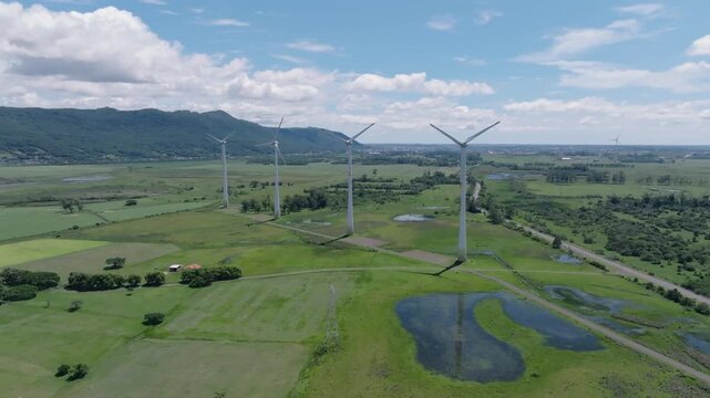 Cinematic aerial orbital shot of wind turbines and electric transmission tower in Osorio Brazil showcasing renewable energy scale and power grid infrastructure. Source: 4K 60fps 10-bit D-Log.