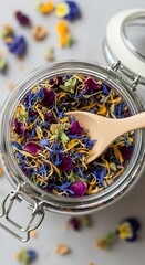 Herbal tea blend in a glass jar with wooden spoon colorful dried flowers and petals