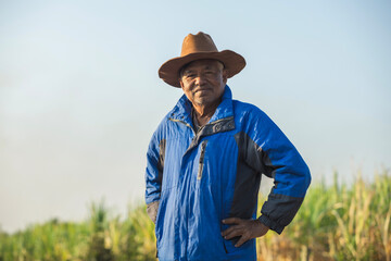 Portrait of elderly farmer wearing winter coat and cowboy hat looking at camera while standing in field.