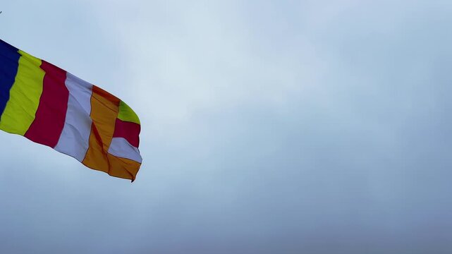 Buddhist flag waving against cloudy blue sky in Sri Lanka