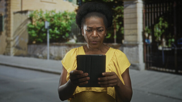 Woman holding tablet with visible hands and focused gaze on a street in front of building; concern focus. - Powered by Adobe