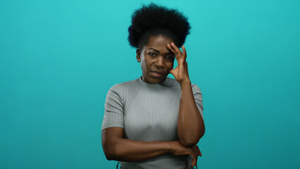 Woman with hand on head showing stress against isolated blue background, conveying emotions and introspection through a thoughtful pose representing contemplation and solitude.