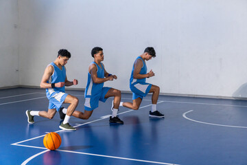 African american teen male basketball players lunging at gym with basketball, white lines