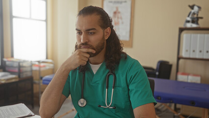 Man doctor with stethoscope hand on chin pensive at clinic desk reviewing patient notes and chart; clinical concern.