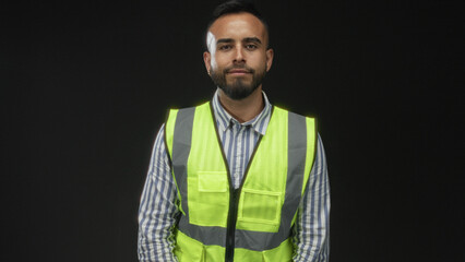 Man with hand on chest wearing neon yellow safety vest and striped shirt in studio with black...