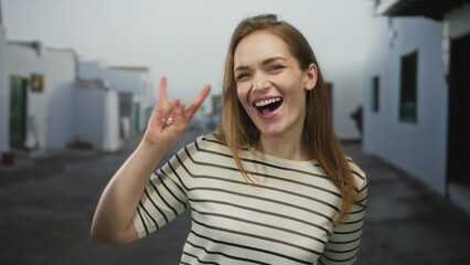 Young caucasian woman making hand rock horns gesture and smiling mouth open on bright outdoor street  fun. © Krakenimages.com
