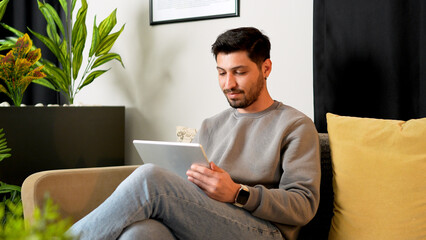 Relaxed man using tablet computer on sofa in modern living room