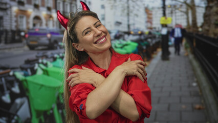 Fototapeta premium Woman in red shirt hugs herself with crossed arms on busy city street lined with green bikes; self love.