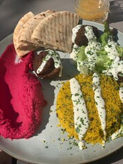 Middle Eastern Mezze Plate with Falafel, Hummus and Pita Bread; Colorful Vegan Mezze Dish with Falafel, Couscous and Fresh Salad; falafel with tahini sauce, hummus, couscous, fresh salad, and pita