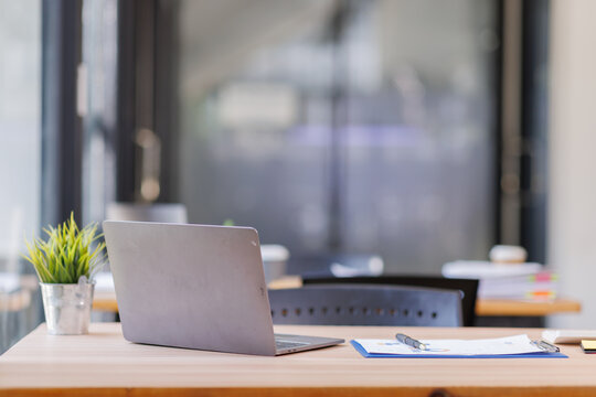 Empty workspace, no people, office desk, with laptop, calculator, graphs, documents on the table.

