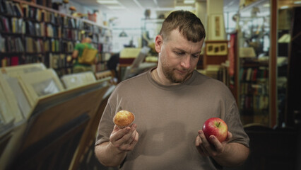 Man holding muffin and apple in library building comparing choices with a frown; indecision choice dilemma.