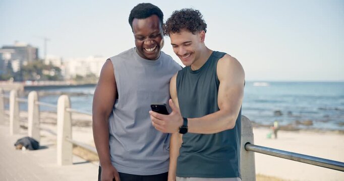 Men, phone and fitness at beach, happy and talk with point, break and share funny meme in summer. People, smartphone and conversation with laugh, joke and video on social media with exercise by sea