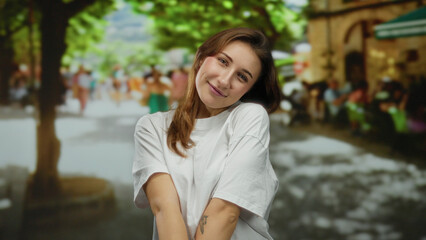 Woman smiling on a vibrant city street surrounded by trees and colorful crowds enjoying a bright day showcasing urban outdoor life and youthfulness.