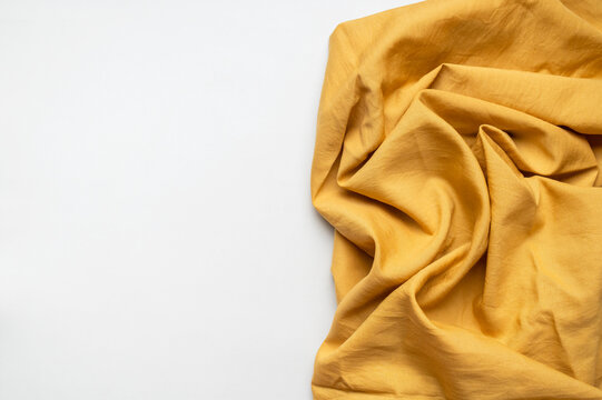 Crumpled natural linen fabric of golden color. Cotton fabric with folds, eco-friendly textiles for clothing, bedding and tablecloths. Abstract background. Fabric texture