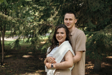 Fototapeta premium Portrait of a young couple in love hugging and kissing in a park. Romantic relationship between a man and a woman. Copy space