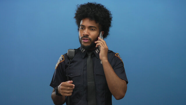African american man in police uniform using smartphone against isolated blue wall background.