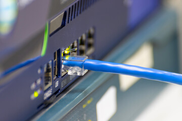 Close-up a blue ethernet cable into a network switch or router. Concept of data connection, internet technology, and IT infrastructure