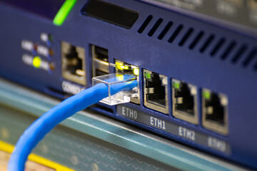 Close-up a blue ethernet cable into a network switch or router. Concept of data connection, internet technology, and IT infrastructure