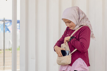 A young Indonesian Muslim woman checking the belongings in her shoulder bag