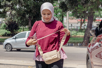 A young Indonesian Muslim woman getting out of a car in a parking lot