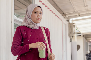 A young Indonesian Muslim woman walking out of a coffee shop