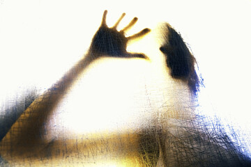 Silueta tras superficie transl&uacute;cida texturizada con mano extendida.aislamiento y presencia, simbolizando tensi&oacute;n emocional, identidad y abstracci&oacute;n humana.