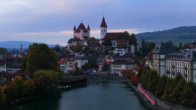 Thun Castle Flusswelle Aare River Schloss Thun Thunersee Switzerland Schweiz Europe Autumn Fall aerial drone morning grey skies yellow birches tree pedestrian walkway Bernese Oberland forwards motion