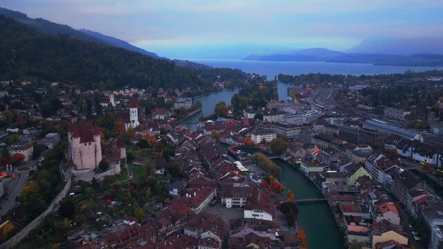 Thun Castle Flusswelle Aare River aerial drone view Schloss Thun Thunersee Switzerland Schweiz Europe Autumn Fall morning grey skies buildings yellow birches tree Bernese Oberland forward pan up
